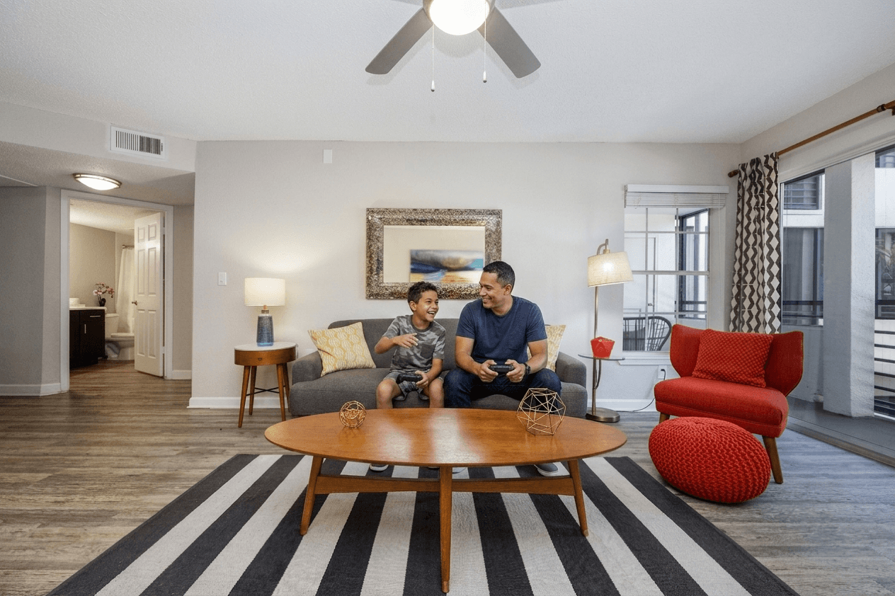Two men are sitting on a couch in a living room.